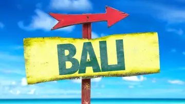 Strzałka kierunkowa wskazuje drogę do Bali. W tle błękitne niebo i morze.
