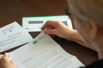 Osoba czyta dokument ZUS. Może to być informacja o zwrocie nadpłaty lub inne pismo z ubezpieczalni.