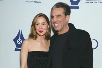 Rose Byrne, znana z wielu filmów, uśmiecha się obok mężczyzny na tle logo New York Film Critics.