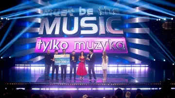 Zwycięzcy "Must be the music. Tylko muzyka" odbierają nagrodę 100 000 zł na scenie, oświetlonej niebieskimi światłami.
