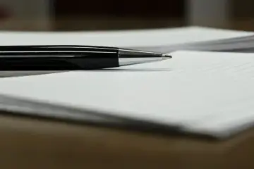 Czarny długopis leży na papierze, gotowy do podpisania ważnego dokumentu, np. pełnomocnictwa.