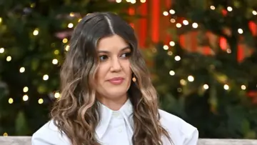 Marta Surnik w białej koszuli, z burzą brązowych loków, na tle świątecznych światełek. Czyżby wspominała męża?