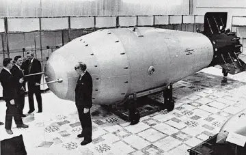 Mężczyźni w garniturach oglądają gigantyczną bombę, która jest symbolem potęgi – car bomba.