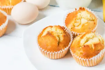 Złociste babeczki z airfryer na białym talerzu, obok jajka. Idealne na szybką przekąskę.