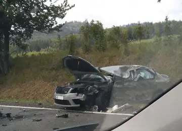 Zniszczony samochód po wypadku, maska otwarta, widoczne uszkodzenia. DKL rejestracja widoczna na przodzie pojazdu.