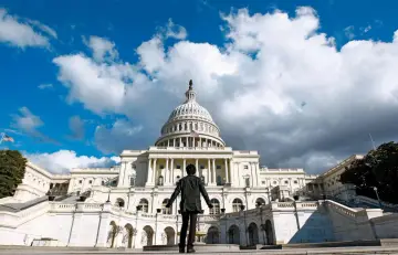 Osoba stoi przed majestatycznym budynkiem Kongresu USA, patrząc na jego kopułę.