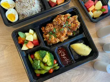 Taca z jedzeniem: panierowany kurczak, puree ziemniaczane, warzywa, owoce i ryż.