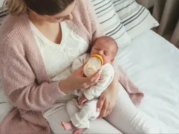 Mama karmi noworodka butelką, ucząc się jak karmić noworodka butelką. Delikatny dotyk i miłość w tym ważnym momencie.