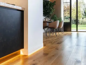 Nowoczesne wnętrze z drewnianą podłogą i subtelnym oświetleniem LED. Eleganckie rozwiązanie co zamiast listew przypodłogowych.