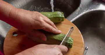 Ręce kroją cukinię na desce. Poznaj jej cudowne cukinia właściwości i dodaj do swojej diety!