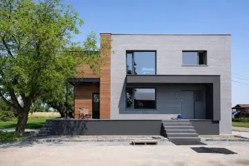 Nowoczesne elewacje domów z lat 70-tych, z betonowych bloków i drewna, z dużymi oknami i tarasem.