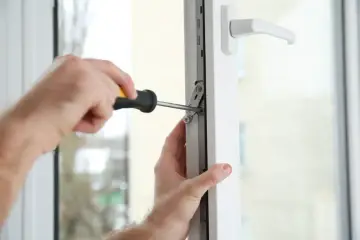 Regulacja drzwi balkonowych uchylnych. Ręce majsterkowicza dokręcają śrubę w mechanizmie okna.