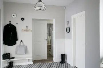 Elegancka sztukateria do polowy sciany w holu, z wieszakami na ubrania i torebkami.