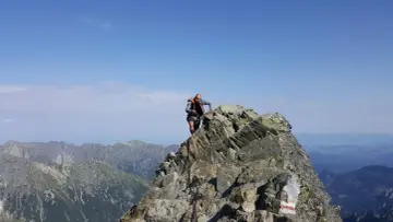 Wspinacz na skalistym szczycie, podziwia widok na Tatry. Czy to już Rysy?