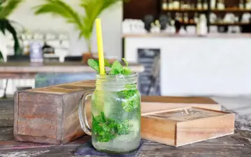 Erfrischender Mojito mit Minze und Eis in einem Glas. So trinkt man Rum an einem heißen Tag.