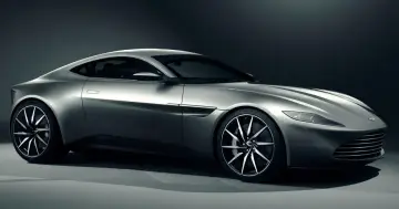 Srebrny Aston Martin DB10, sportowy samochód o aerodynamicznej sylwetce, prezentuje swoje eleganckie linie i felgi.