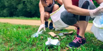 Aktywne plogging: dwie kobiety w rękawiczkach zbierają śmieci do worka podczas biegu.