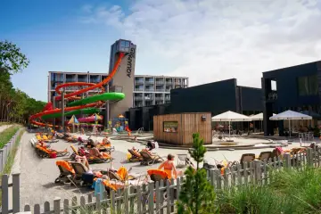 Słoneczny dzień w Mielnie Aquapark. Kolorowe zjeżdżalnie wodne, leżaki z opalającymi się ludźmi i baseny tworzą wakacyjną atmosferę.