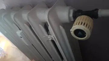 Biały grzejnik żeliwny z termostatem Danfoss. Awaria ogrzewania w Zabrzu? Zimno w mieszkaniu.