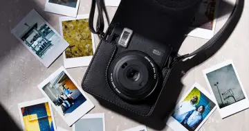 Czarny aparat Instax w etui, otoczony natychmiastowymi zdjęciami. Dowiedz się, jak robić zdjęcia Instax, tworząc własne, unikalne wspomnienia.
