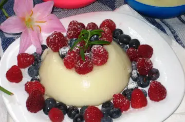 Panna cotta z malinami i borówkami, posypana cukrem pudrem. Idealny deser, który możesz przygotować według prostego legumina przepis.