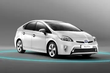 Biały Prius 3, hybrydowy samochód, prezentuje się elegancko na tle szarego tła, otoczony niebieską poświatą.