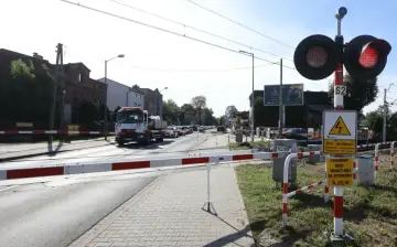 Przejazd kolejowy z zaporami i czerwonymi światłami. Samochód ciężarowy czeka na przejazd.