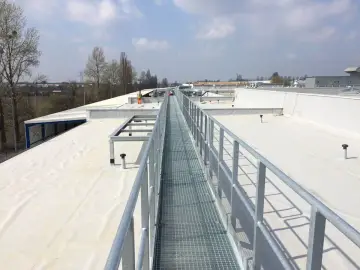 Szeroki dach pokryty białą membraną TPO, z metalową kładką serwisową biegnącą wzdłuż.