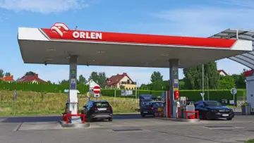 Stacja Orlen z dystrybutorami paliwa i samochodami. Zastanawiasz się, ile zarabia kasjer na Orlenie?