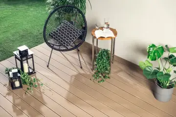 Nowoczesne deski kompozytowe to świetny pomysł, czym wyłożyć balkon. Wygodne krzesło, stolik i latarenki tworzą przytulną atmosferę.
