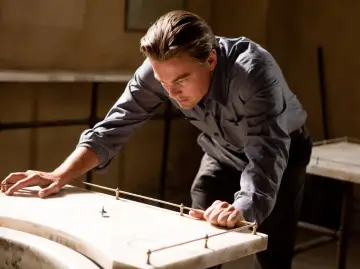 Leonardo DiCaprio pochyla się nad stołem, obserwując wirujący bączek. Czy to sen? Incepcja co to?