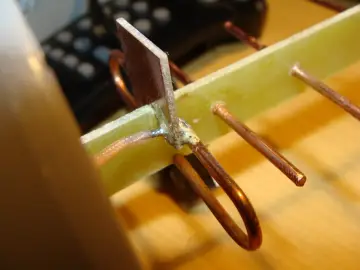 Elementy DIY anteny do telewizora z puszki: miedziane przewody, płytka drukowana i lut.
