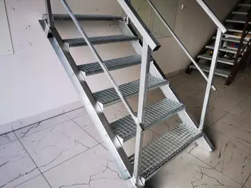Solidne schody metalowe do piwnicy, wykonane z kraty pomostowej, zapewniają bezpieczne zejście.