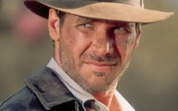 Harrison Ford w kapeluszu i skórzanej kurtce, z widocznymi śladami przygód. Wiek nie przeszkadza mu w dalszych wyprawach.