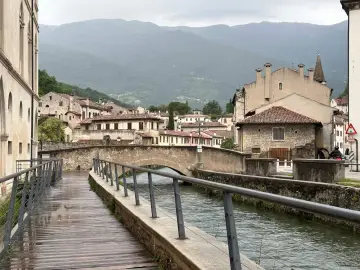 Passeggiata lungo il canale, tra antichi palazzi e ponti in pietra. Ecco cosa vedere a Vittorio Veneto, con le montagne sullo sfondo.