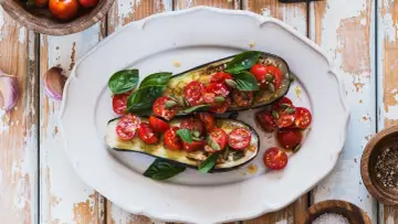 Melanzane ripiene vegetariane con pomodorini, basilico e semi di zucca, un piatto colorato e saporito.