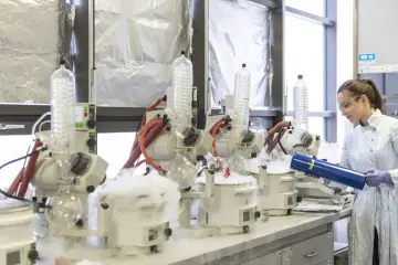 Naukowczyni w laboratorium z aparaturą do destylacji. Dymiące urządzenia symbolizują uniwersalizm nauki, która przekracza granice.