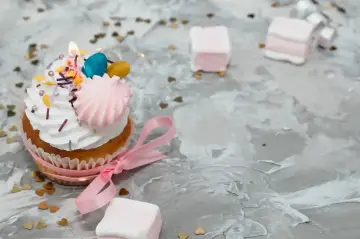 Uroczy cupcake z różową wstążką i ozdobami, idealny jako alternatywa dla tortu urodzinowego.