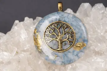 Colgante de orgonita con árbol de la vida dorado sobre fondo de cuarzo. El significado de la orgonita se refleja en su energía protectora.