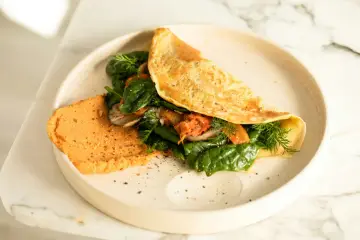 Omlet z air fryera z farszem ze szpinaku, pieczarek i kimchi. Obok porcja pomarańczowego hummusu.
