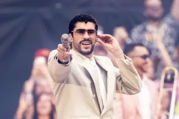Bad Bunny w beżowym garniturze, z mikrofonem w dłoni, czuje energię tłumu.