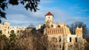 Ruiny zamku na wzgórzu, jeden z największych zamków w Polsce, z wieżą i ceglanymi arkadami.