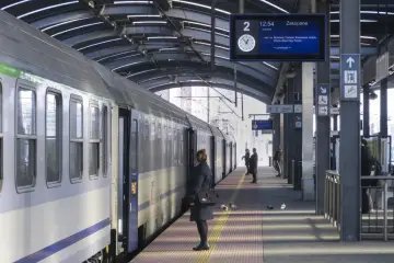 Pociąg na peronie, tablica informacyjna z trasą do Zakopanego, pasażerowie.