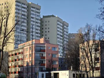 Bloki mieszkalne w słońcu. Czy spółdzielnia płaci podatek od nieruchomości? W tle wysokie budynki, na pierwszym planie różowy budynek z balkonami.