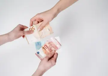 Dwie ręce przekazują sobie banknoty euro. To obecna waluta holandii, używana do codziennych transakcji.