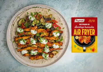 Pyszny kurczak gyros z warzywami i sosem na tortilli, obok paczka przyprawy Prymat Air Fryer.