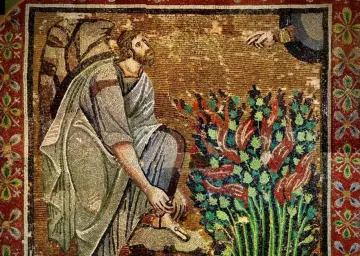 Mojżesz zdejmuje sandały przed gorejącym krzewem w biblijnej opowieści. Ręka Boga wyciąga się z nieba.