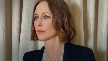 Vera Farmiga, znana z wielu filmów, seriali i programów, w eleganckim czarnym żakiecie i perłach.