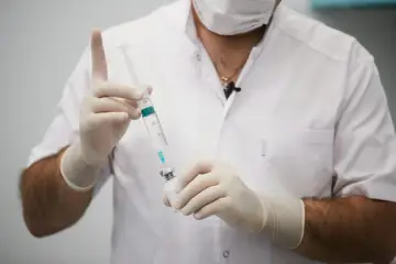 Lekarz w białym kitlu i rękawiczkach przygotowuje zastrzyk. To może być część terapii, np. chemiczna kastracja.