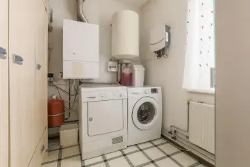 W tym pomieszczeniu gospodarczym znajduje się pralka, suszarka, bojler i szafa.
